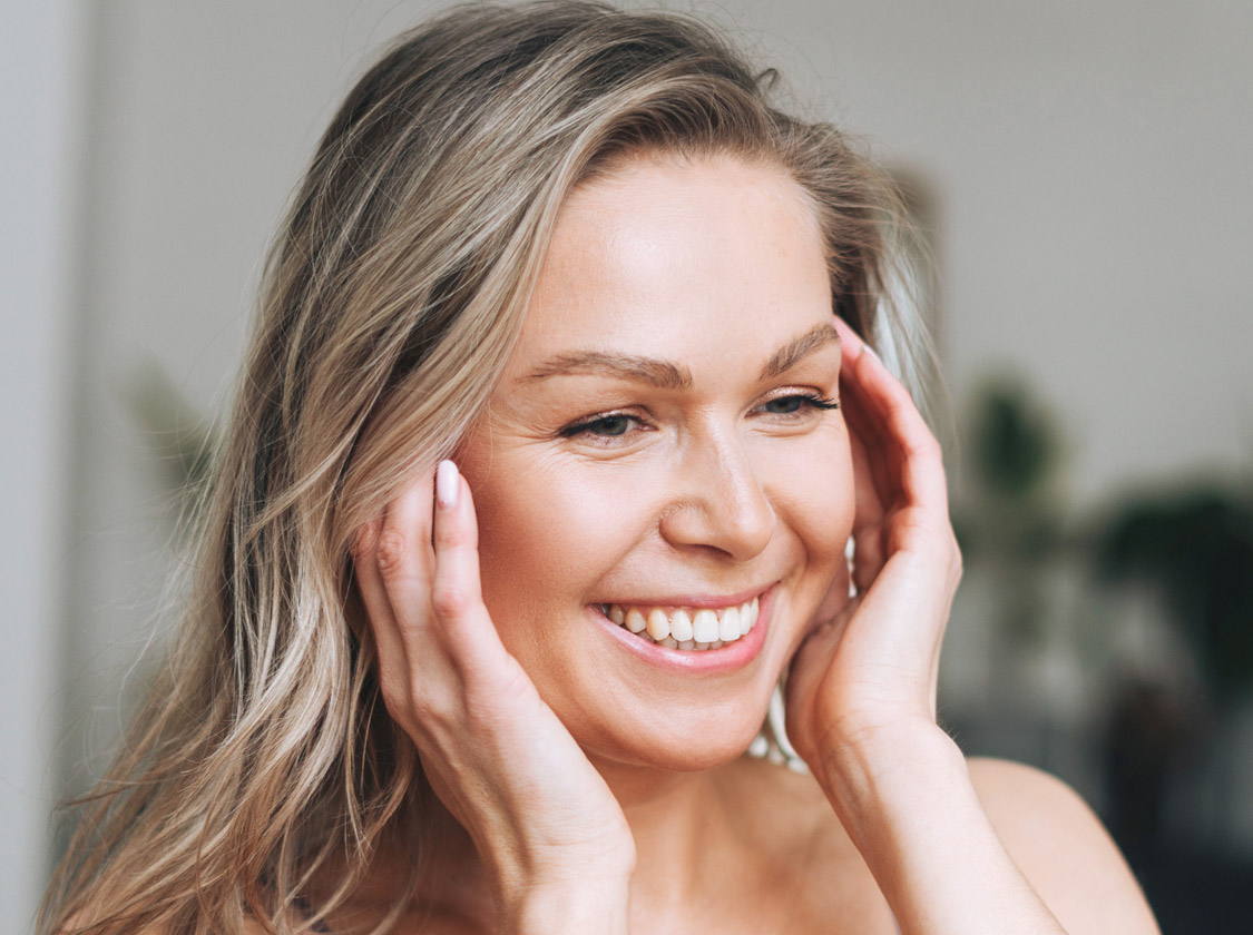 Smiling blonde woman resting her hands on her cheeks